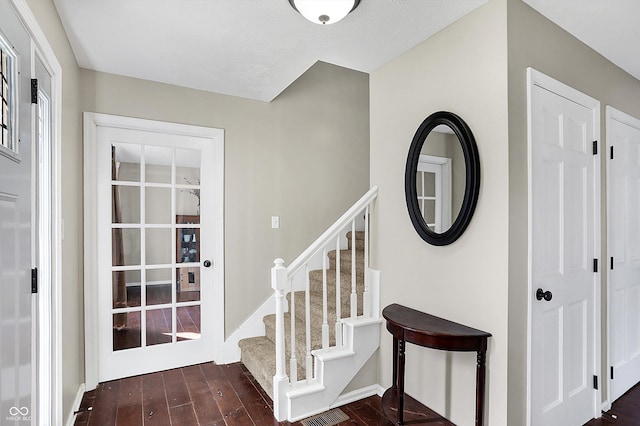 stairway featuring wood finished floors and visible vents