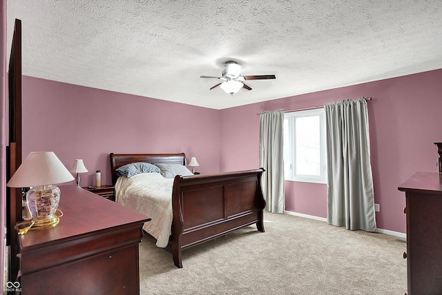 bedroom with a textured ceiling, light colored carpet, baseboards, and ceiling fan