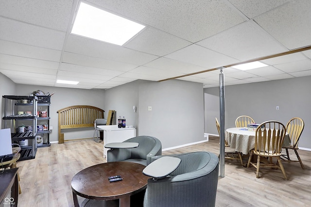 interior space featuring baseboards, a paneled ceiling, and light wood-style floors