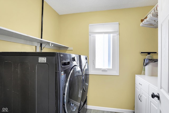 clothes washing area featuring baseboards, a textured ceiling, independent washer and dryer, and cabinet space