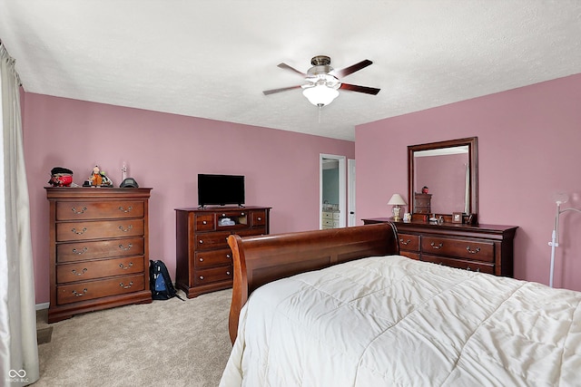 bedroom featuring ceiling fan, light colored carpet, and a textured ceiling