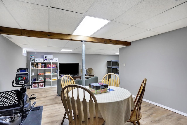 dining area with a drop ceiling, light wood-style flooring, and baseboards