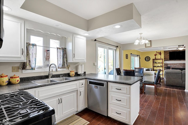 kitchen featuring a peninsula, a sink, dishwasher, dark countertops, and open floor plan