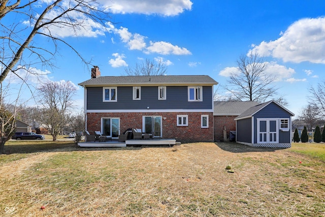 rear view of house with an outbuilding, a wooden deck, a yard, a chimney, and brick siding