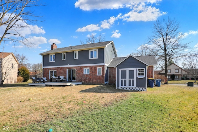 back of property featuring a wooden deck, a lawn, a chimney, and brick siding