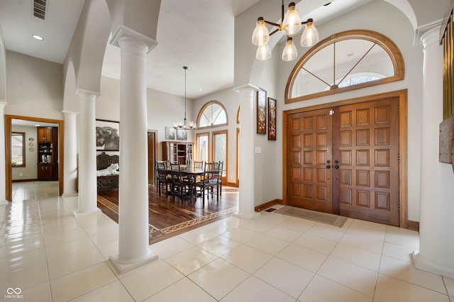 foyer featuring tile patterned flooring, visible vents, ornate columns, and a chandelier