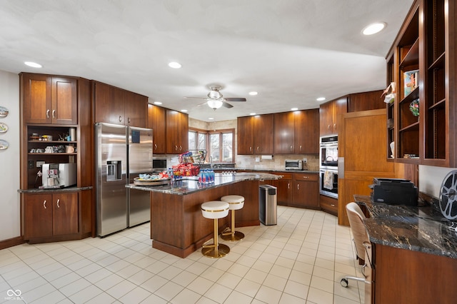 kitchen with light tile patterned floors, open shelves, appliances with stainless steel finishes, a kitchen bar, and a center island