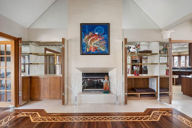 unfurnished living room featuring tile patterned floors, decorative columns, lofted ceiling, and a tile fireplace