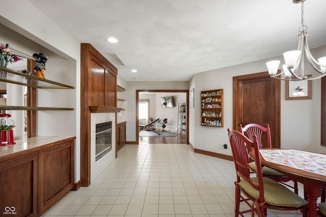 dining room featuring visible vents, a large fireplace, baseboards, a chandelier, and light tile patterned floors