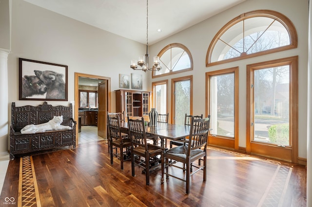 dining room with an inviting chandelier, a high ceiling, and dark wood-style floors