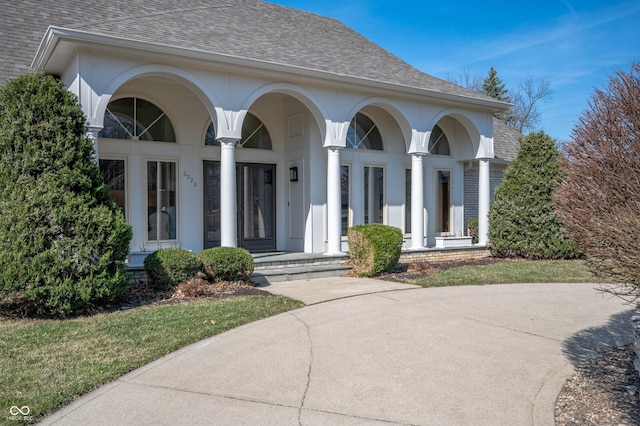 view of front of house with stucco siding, brick siding, a porch, and a shingled roof