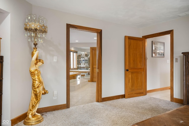 bedroom with baseboards, visible vents, ensuite bath, light tile patterned flooring, and light carpet