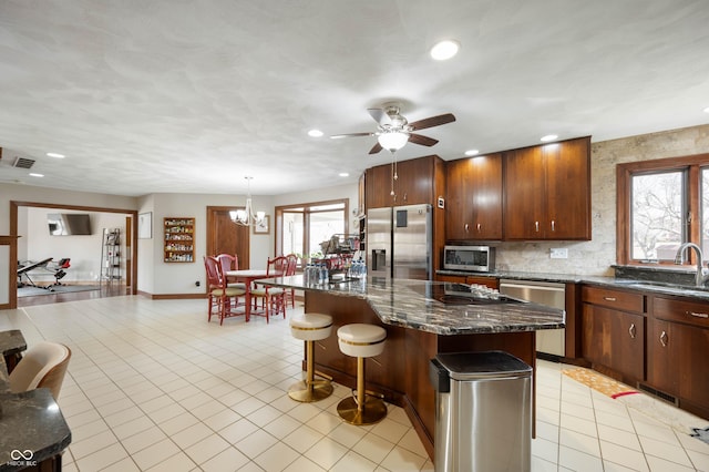 kitchen with a center island, a kitchen bar, light tile patterned floors, appliances with stainless steel finishes, and a sink