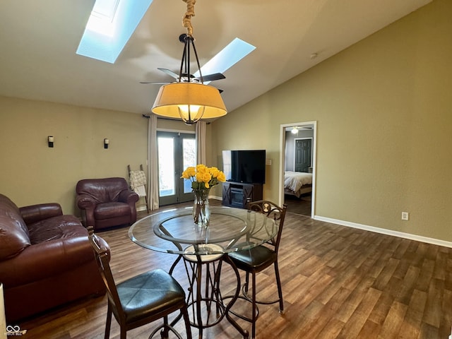 living area featuring vaulted ceiling with skylight, wood finished floors, and baseboards