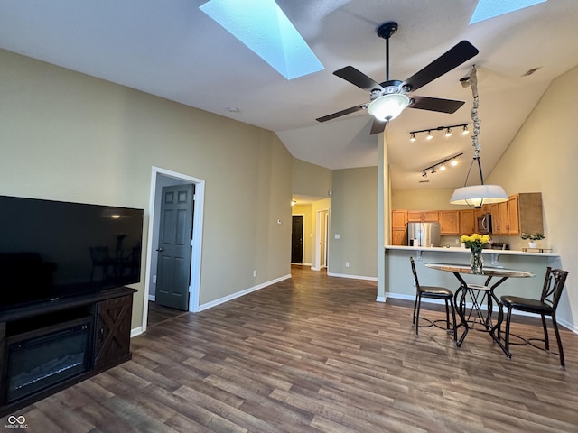 interior space featuring dark wood-type flooring, ceiling fan, baseboards, a skylight, and high vaulted ceiling