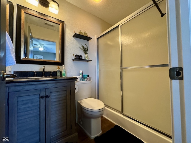 full bath with vanity, visible vents, a shower stall, toilet, and a textured wall