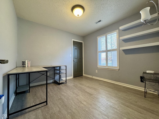 home office with baseboards, wood finished floors, visible vents, and a textured ceiling