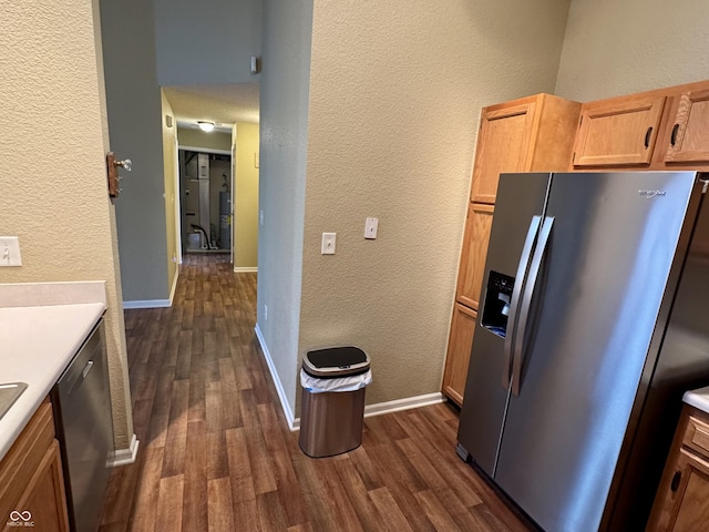 kitchen with dark wood-type flooring, appliances with stainless steel finishes, light countertops, and a textured wall