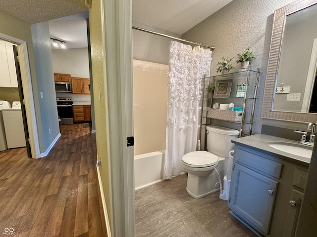 bathroom featuring toilet, a textured ceiling, wood finished floors, washing machine and clothes dryer, and a textured wall