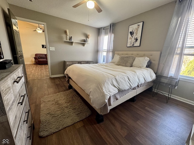 bedroom with dark wood-type flooring, a ceiling fan, and baseboards