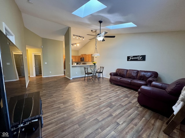 living room featuring high vaulted ceiling, a ceiling fan, dark wood finished floors, a skylight, and baseboards