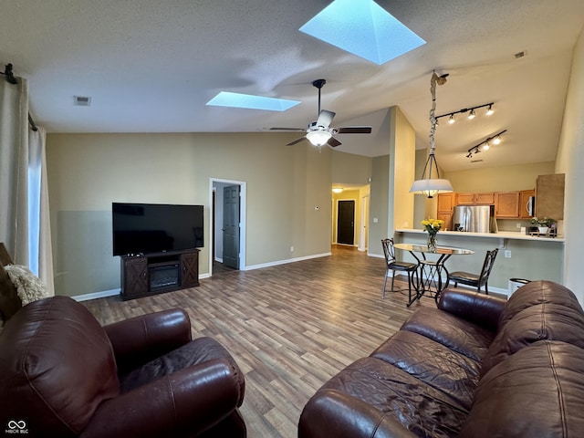 living area with visible vents, lofted ceiling with skylight, a textured ceiling, and wood finished floors