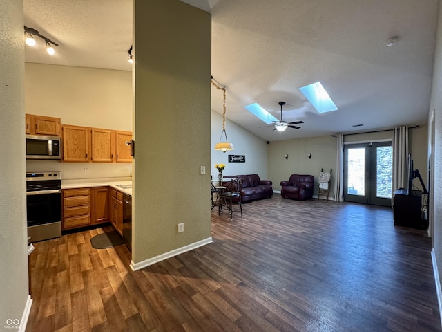 kitchen featuring dark wood-style floors, open floor plan, vaulted ceiling with skylight, and appliances with stainless steel finishes