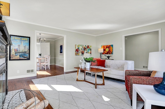 living room with visible vents, wood finished floors, crown molding, and a chandelier