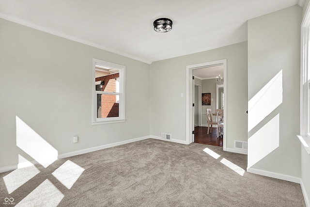 carpeted empty room featuring visible vents, an inviting chandelier, crown molding, and baseboards