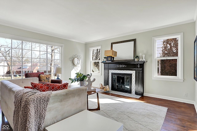 living room featuring baseboards, wood finished floors, ornamental molding, and a tile fireplace