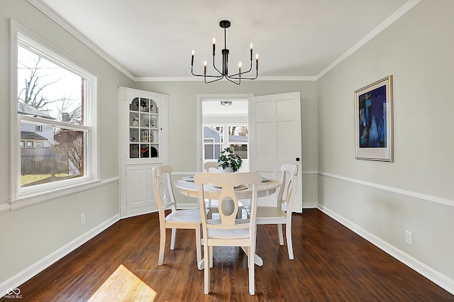 dining room with an inviting chandelier, crown molding, wood finished floors, and baseboards