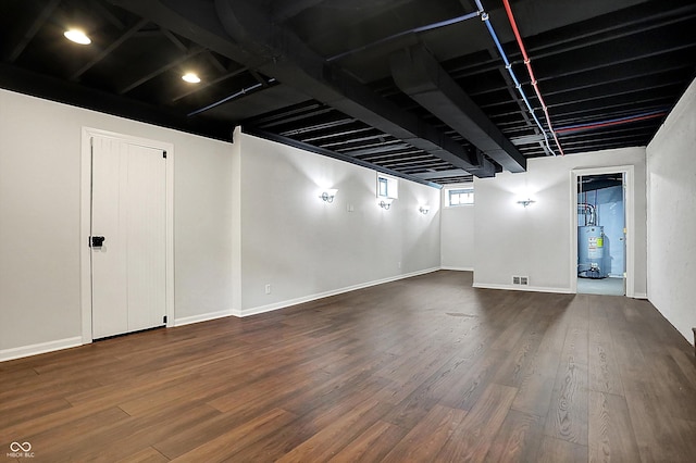 basement featuring water heater, baseboards, and wood finished floors