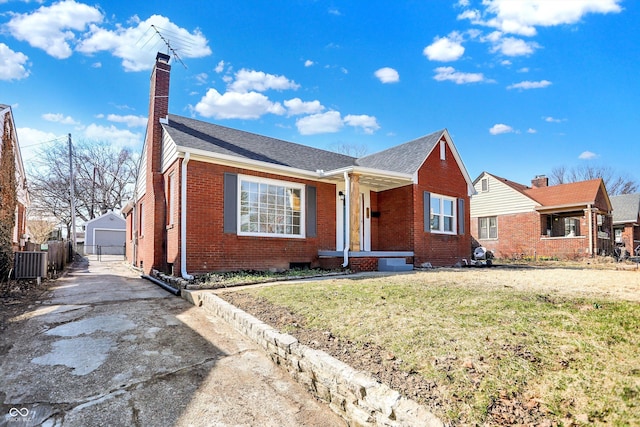 view of front of home featuring brick siding, a front lawn, fence, a chimney, and an outbuilding