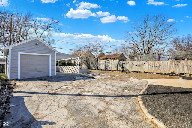 view of yard featuring aphalt driveway, an outdoor structure, a garage, and fence