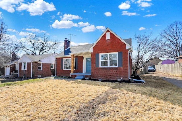 bungalow-style house featuring brick siding, a chimney, a front lawn, and fence