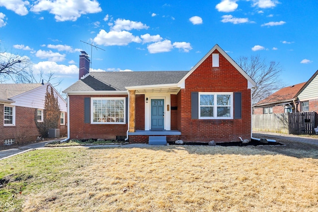 bungalow-style house with brick siding, a front lawn, fence, central AC unit, and a chimney