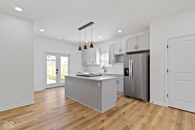 kitchen featuring tasteful backsplash, a kitchen island, light countertops, french doors, and stainless steel fridge