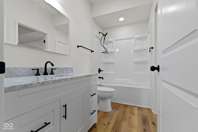 bathroom with toilet, recessed lighting, wood finished floors, vanity, and  shower combination