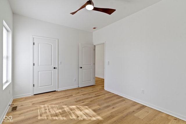 unfurnished bedroom featuring ceiling fan, visible vents, baseboards, and wood finished floors