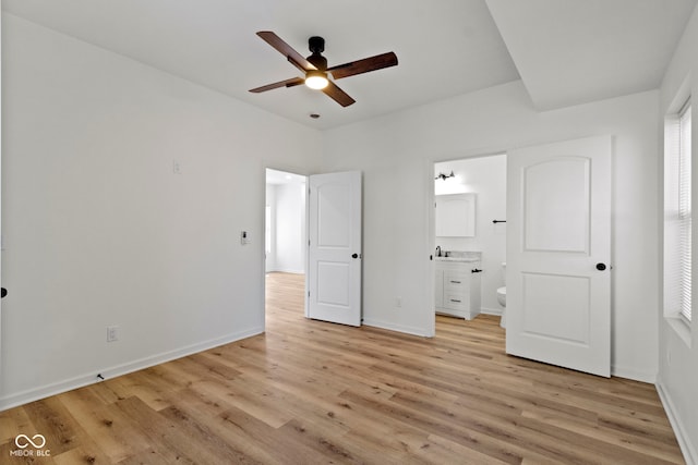 unfurnished bedroom featuring light wood finished floors, ceiling fan, baseboards, ensuite bathroom, and a sink