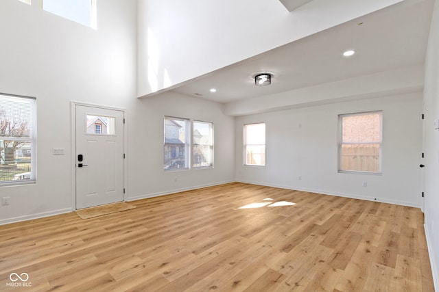 foyer entrance featuring a high ceiling, recessed lighting, baseboards, and light wood finished floors