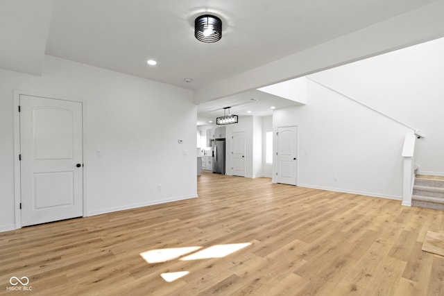 unfurnished living room featuring stairway, recessed lighting, baseboards, and light wood-type flooring