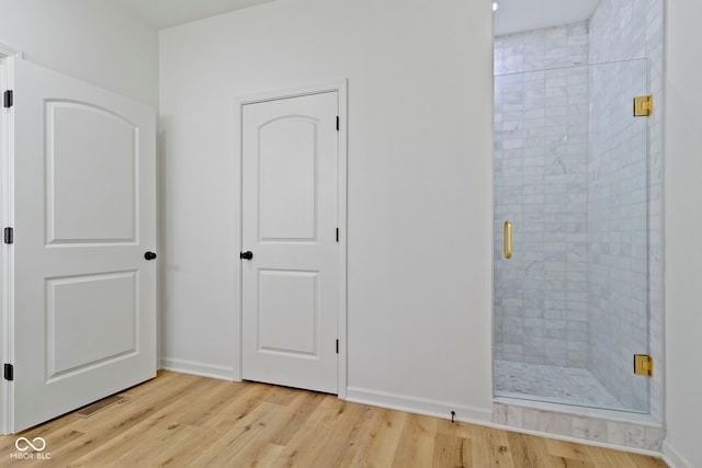 unfurnished bedroom featuring ensuite bath, baseboards, and light wood-type flooring