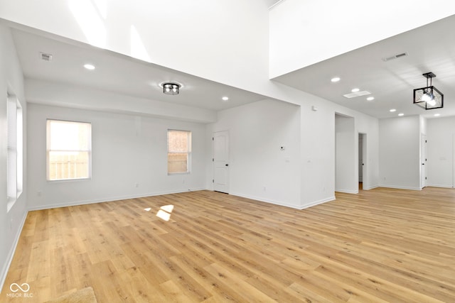 empty room featuring a wealth of natural light, light wood-type flooring, baseboards, and recessed lighting