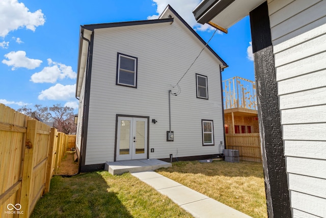 back of property with french doors, cooling unit, a yard, and a fenced backyard