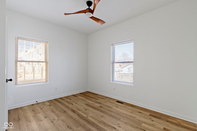 spare room featuring visible vents, light wood-style flooring, baseboards, and a ceiling fan