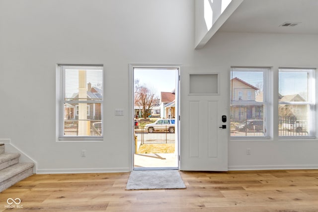 foyer featuring visible vents, baseboards, wood finished floors, and stairs