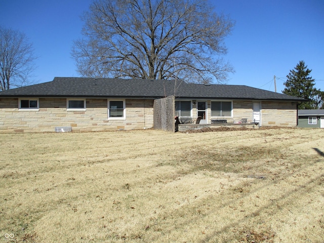 view of front of property featuring stone siding, roof with shingles, and a front lawn