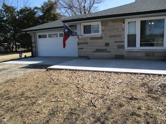 view of property exterior with an attached garage, stone siding, driveway, and roof with shingles