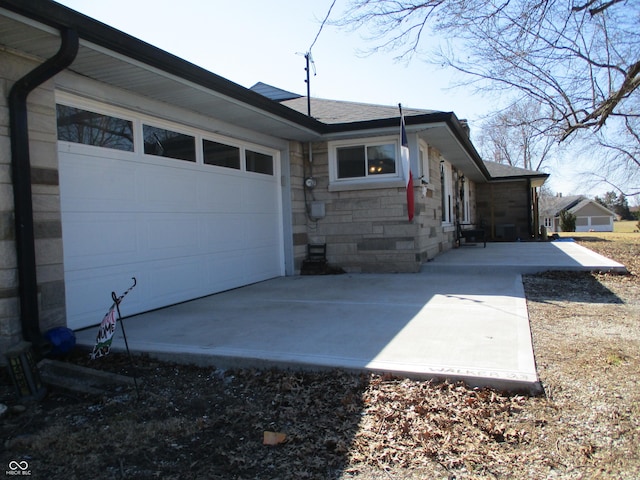 view of home's exterior with a garage, stone siding, and concrete driveway